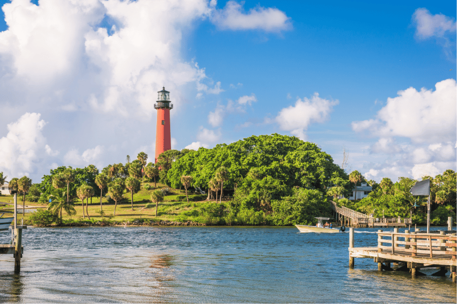 Red lighthouse in Jupiter, FL near the water with boats and a dock
