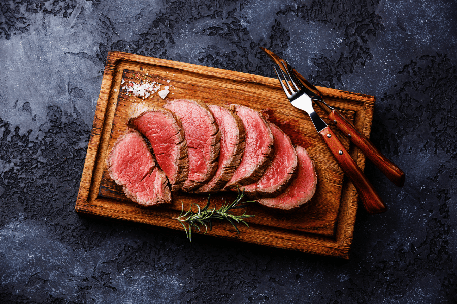 cut steak with salt and utensils on a wood board