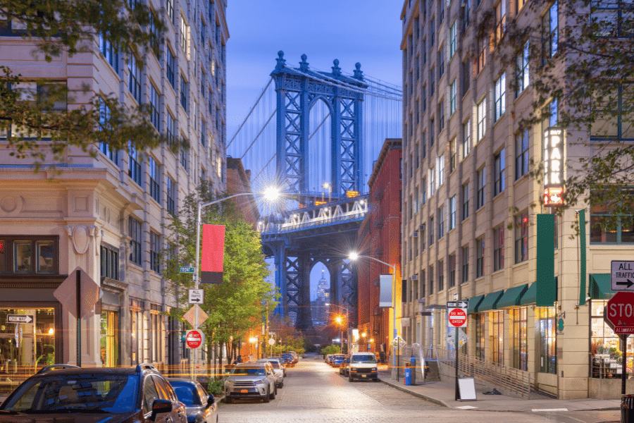 The brooklyn bridge in between downtown city buildings and brownstone homes in Brooklyn