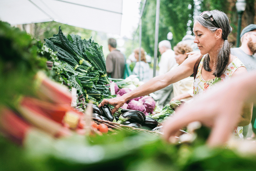 Farmers Market Woman looking at fresh vegetables at a farmers market