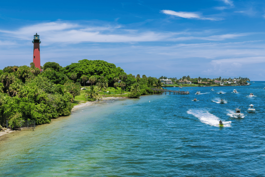 Jupiter Florida Inlet Lighthouse on a sunny day near the ocean with boats and lush greenery