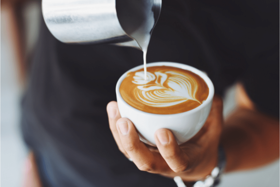 A cafe latte poured beautifully with a tree design