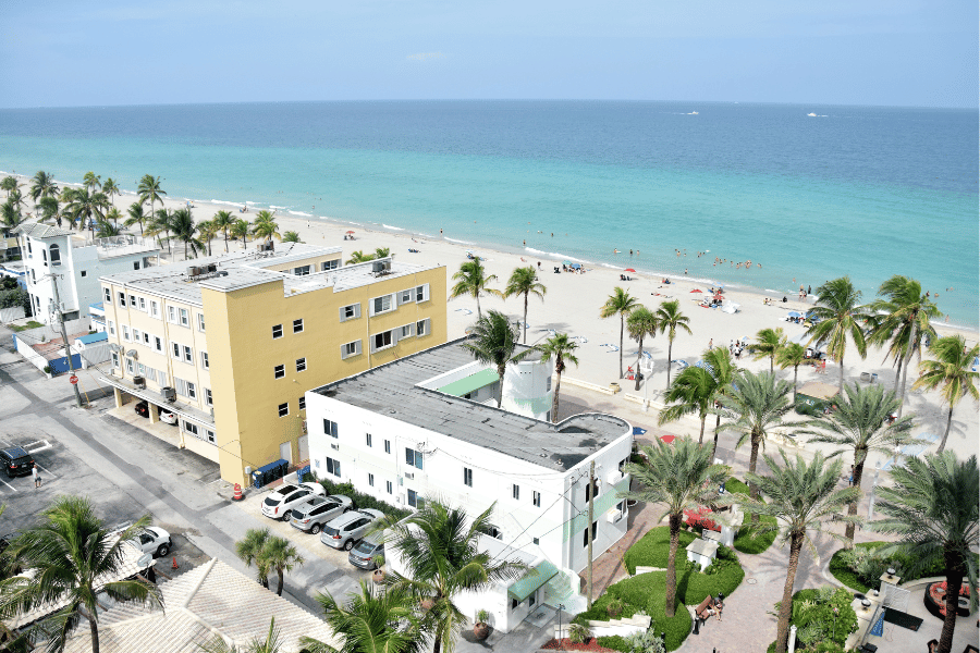 Hollywood, FL aerial view of condos, cars, and palm trees near the blue Atlantic ocean