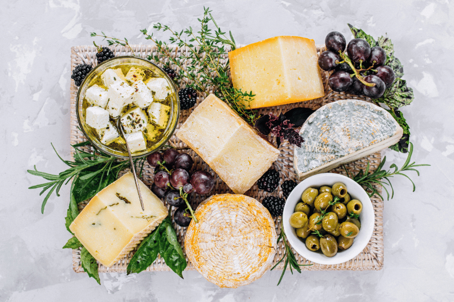 market cheese herbs grapes and olives on a board