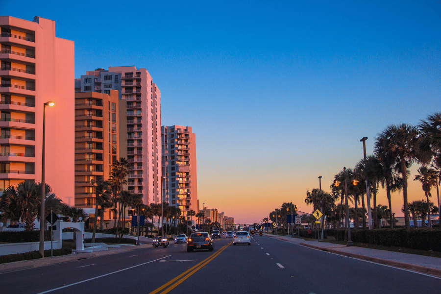 Daytona Beach Road Road in Daytona Beach, FL during sunset with palm trees and cars driving