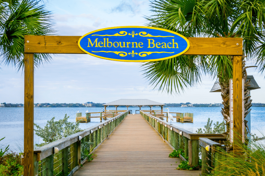 Melbourne Beach Image of Melbourne beach from behind the blue welcome sign arching over the wooden walkway