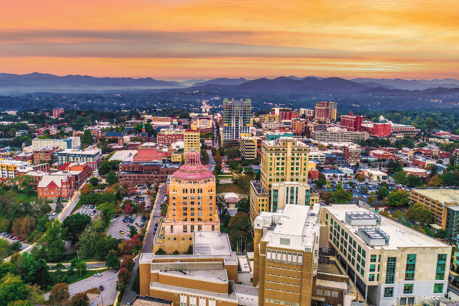 Asheville NC Birdseye view with orange sunset and mountains in background