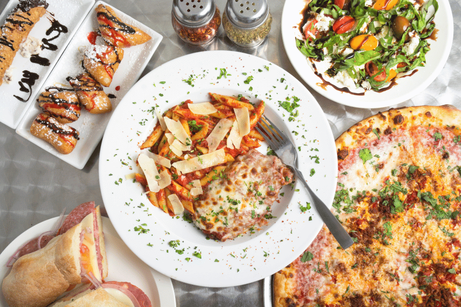 Italian-food (1).png spread of Italian food on a table with pizza, pasta, and salad, and