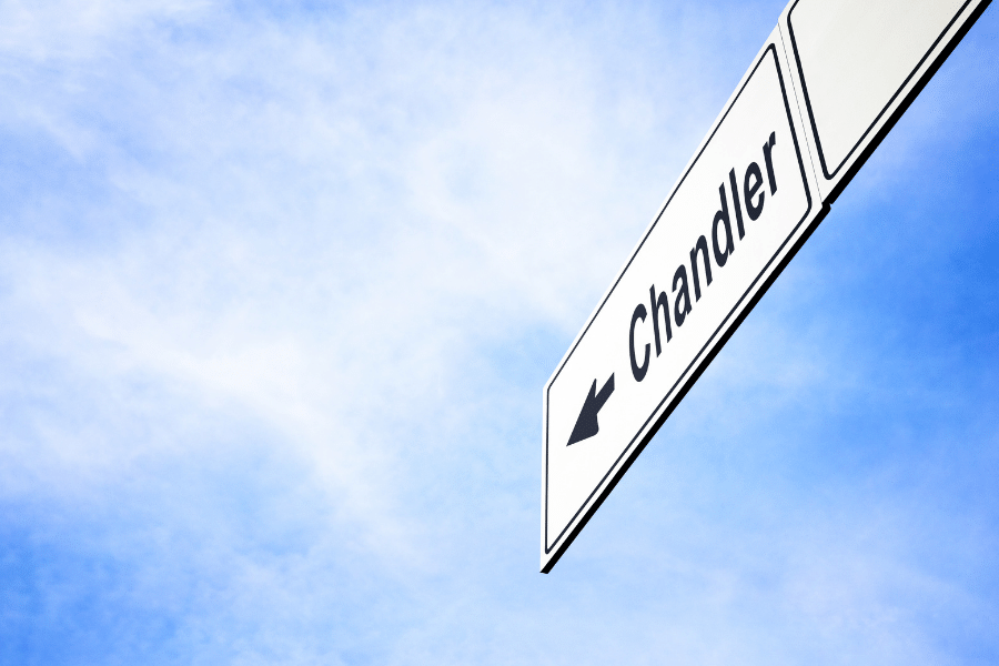 A street sign that says Chandler on a sunny day with clouds in the sky