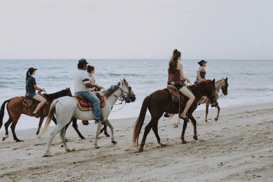 Riding Horses on the Beach Group of horseback riders on the beach during low tide